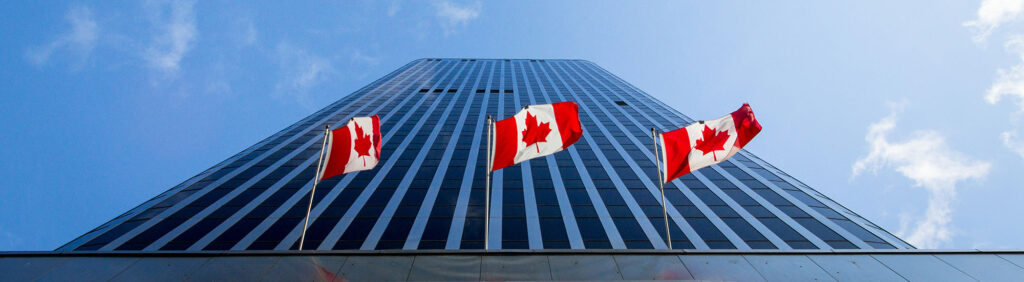 Three Canadian flags in front of a business building in Ottawa, Ontario, Canada. Ottawa is the capital city of Canada, and one of the main economic, political and business hubs of North America
